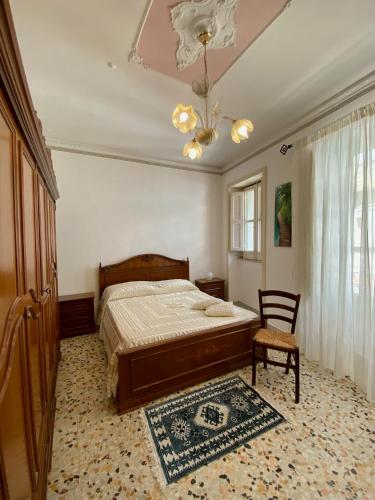 a bedroom with a bed and a chair and a chandelier at Casa Tanina in Scordia