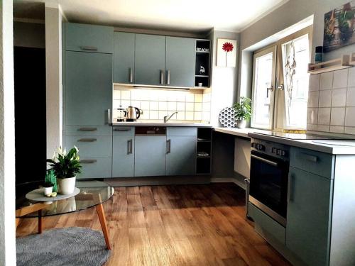 a kitchen with blue cabinets and a table in it at Rostock hautnah erleben - schöne Maisonette 2OG in Rostock