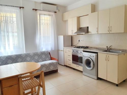 uma cozinha com um sofá, uma mesa e um fogão em Apartment Emma em Velipojë