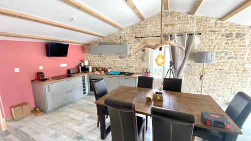 a kitchen and dining room with a wooden table and chairs at Le Grenier - Gîte de Charme La Rochelle in Saint-Médard-dʼAunis