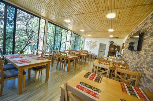 un restaurante con mesas y sillas de madera y ventanas en Madin Eco Hotel, en Debed