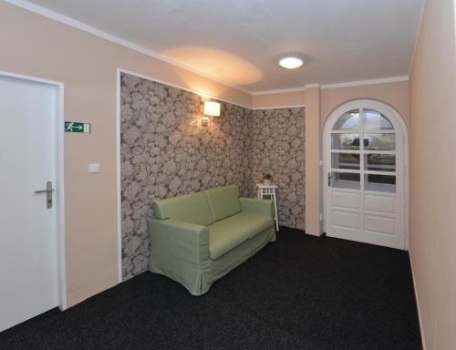 a living room with a green chair and a door at Wellness Pension Fulda Černý Důl in Cerny Dul