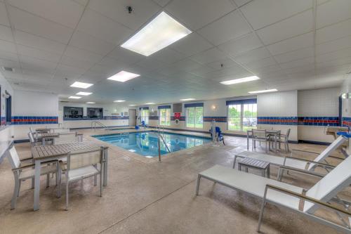 a swimming pool with tables and chairs in a building at Country Inn & Suites by Radisson, Crystal Lake, IL in Crystal Lake