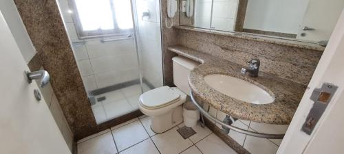 uma casa de banho com um lavatório, um WC e um espelho. em Cond. Mediterrâneo Flat no Rio de Janeiro