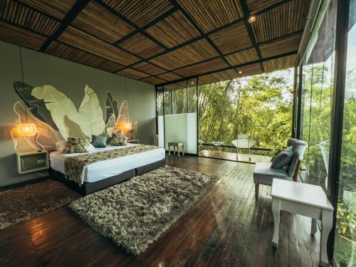 a bedroom with a bed and a large window at Hotel Terra Tacuara in Armenia