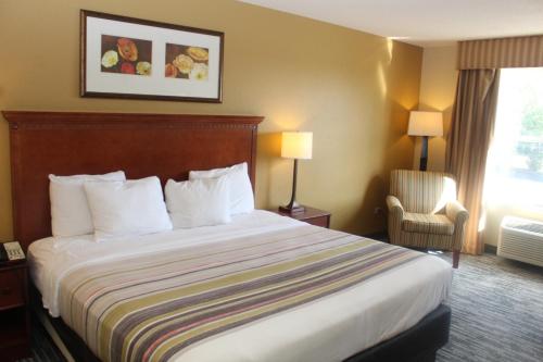 a hotel room with a bed and a chair at Country Inn & Suites by Radisson, Crystal Lake, IL in Crystal Lake