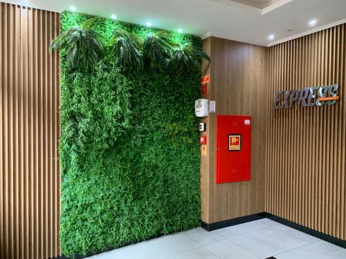 a green wall in a lobby with a red phone booth at Novo apto com garagem no centro de Passo Fundo RS in Passo Fundo
