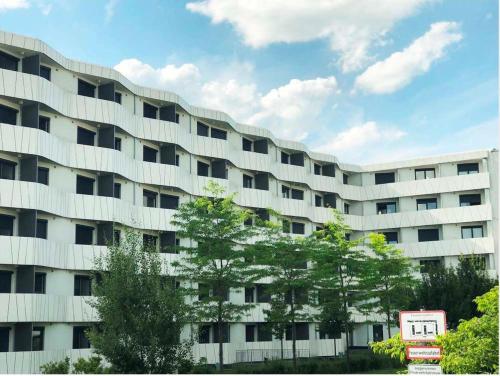 a large white building with trees in front of it at Myroom Business Apartment Nähe Messe München in Munich