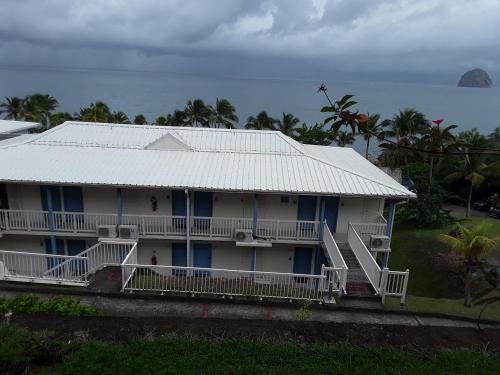 a white house with a white roof and the ocean at La Perle du Rocher in Le Diamant