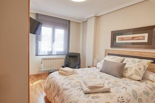 a bedroom with a bed with a chair and a window at AVA-2 in Arévalo