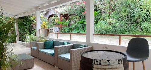 un porche con sillas, mesa y árboles en Appartement "grand Hibiscus" jardin privé, en Le Lamentin