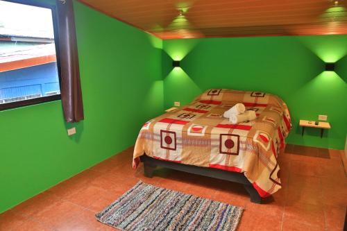 a green bedroom with a bed with a stuffed animal on it at Mangifera Hostel in Grecia