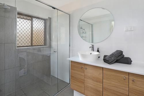 a bathroom with a sink and a shower with a mirror at CANAL7-ON THE MOOLOOLABA CANAL! in Mooloolaba