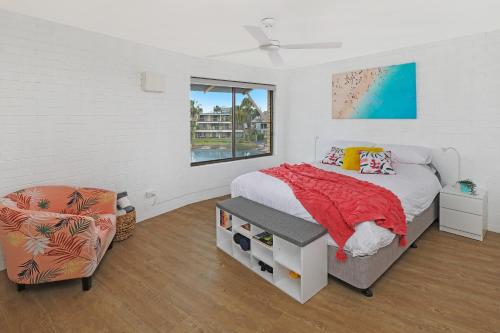 a bedroom with a bed and a chair and a window at CANAL7-ON THE MOOLOOLABA CANAL! in Mooloolaba