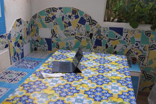 a laptop sitting on a table with a mosaic wall at Villetta partenopea a pochi passi dal mare in Meta