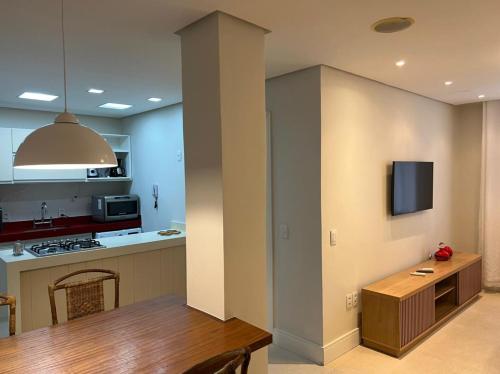 a kitchen with a table and a tv on a wall at Melhor localização Leblon, apartamento reformado in Rio de Janeiro