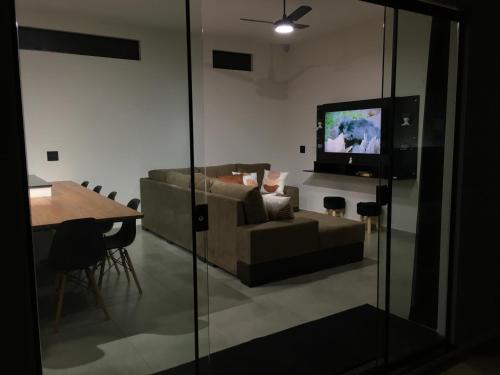 a living room with a couch and a table and a television at Cantinho Estrelado - Casa automatizada com ALEXA in Brotas