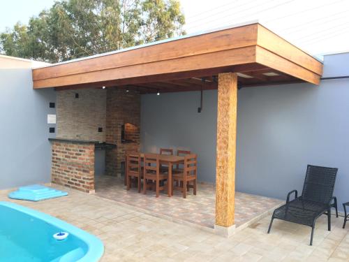 a pavilion with a table and chairs and a swimming pool at Cantinho Estrelado - Casa automatizada com ALEXA in Brotas