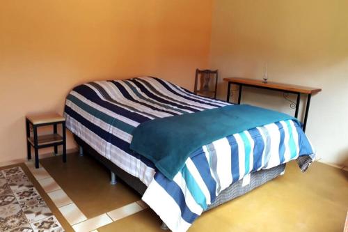 a bedroom with a bed with a striped blanket on it at Recanto do Ipê in Extrema