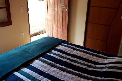 a bed with a quilt on it next to a window at Recanto do Ipê in Extrema
