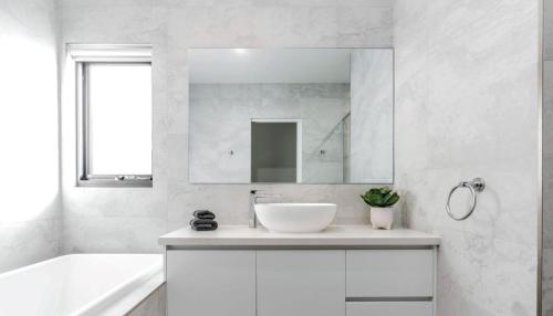 uma casa de banho branca com um lavatório e um espelho em Luxury on Bayview Wifi Linen included em Inverloch