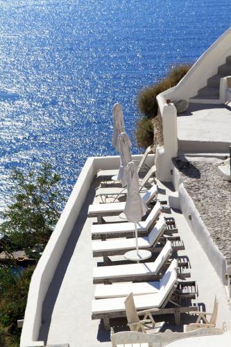 a row of lounge chairs with the ocean in the background at Oia Mare Villas in Oia