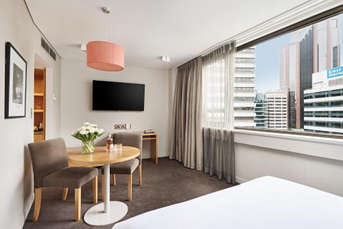 ein Hotelzimmer mit einem Tisch und einem großen Fenster in der Unterkunft View Sydney in Sydney