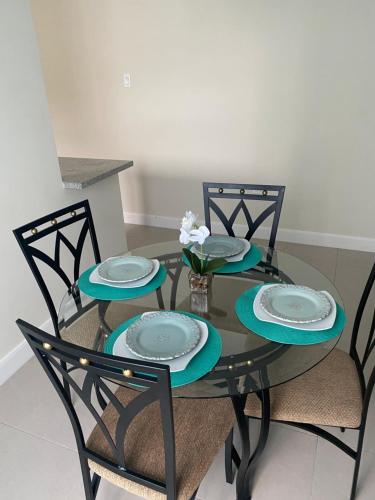 a glass table with two chairs and two plates on it at Natalia’s Sweet Oasis in Lucea