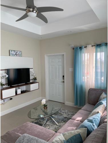 a living room with a couch and a glass table at Natalia’s Sweet Oasis in Lucea