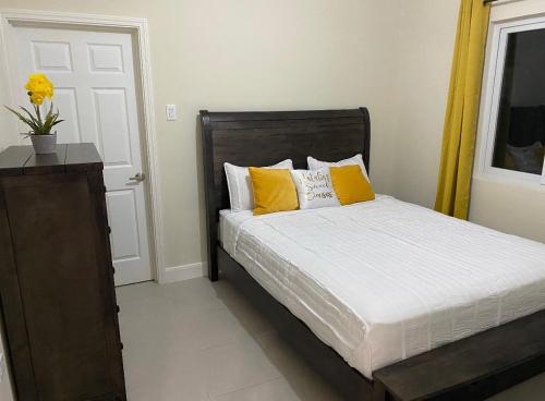 a bedroom with a bed with yellow pillows at Natalia’s Sweet Oasis in Lucea