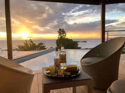 a table with two bottles of alcohol and two chairs at Calypso Bay in Bouillante