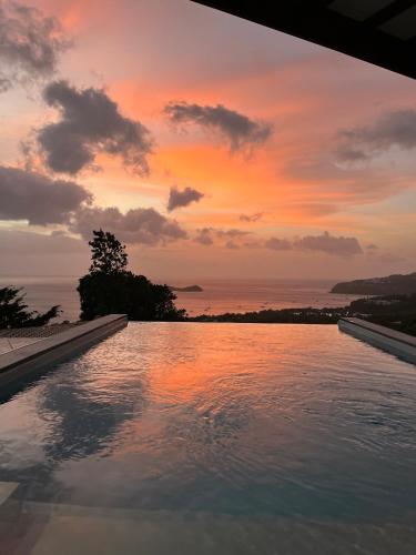 a swimming pool with a sunset in the background at Calypso Bay in Bouillante