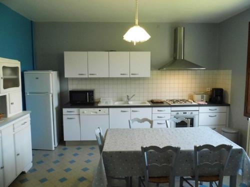 une cuisine avec des armoires blanches et une table avec des chaises dans l'établissement Charmante maison au cœur du Périgord avec jardin clos, Wifi, garage, proche de la Dordogne et sites historiques - FR-1-616-42, au Buisson de Cadouin