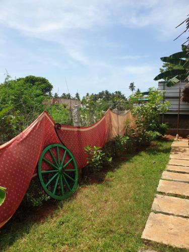 a garden with a red cart in the grass at TANJORE HOME STAY in Thanjāvūr