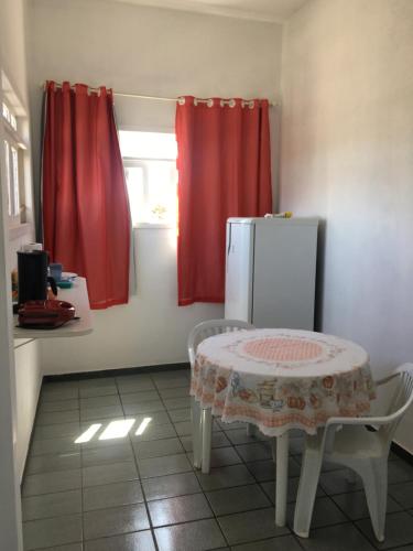 a kitchen with a table and a refrigerator and a window at Suíte aconchegante na praia in Jacaraípe