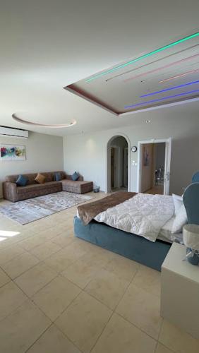 a bedroom with a large bed and a couch at فيلا بشاطي رملي خاص ومسبح عالبحر - درة العروس شاطي البردايس in Durat  Alarous