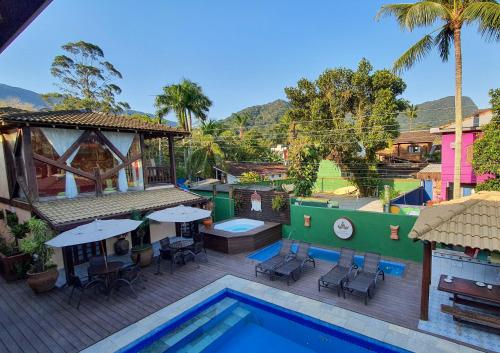 una piscina con mesas y sillas junto a un edificio en Pousada Pura Vida Maresias en Maresias