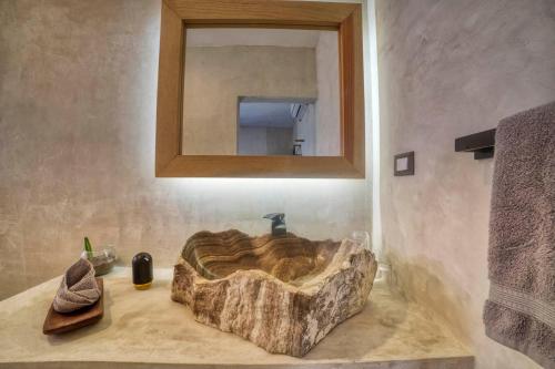 a bathroom with a stone sink with a mirror at Hotel Boutique Can Cocal El Cuyo in El Cuyo