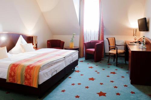 a hotel room with a bed and a desk and chairs at Stadthotel Stern in Wismar