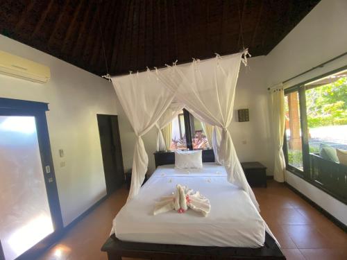 a bedroom with a canopy bed with towels on it at Badini Homestay Pemuteran Bali in Pemuteran