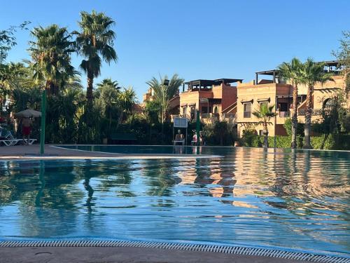 een groot zwembad met palmbomen en gebouwen bij atlas golf resort marrakech " Maison à 03 chambres avec jardin privé " in Marrakesh
