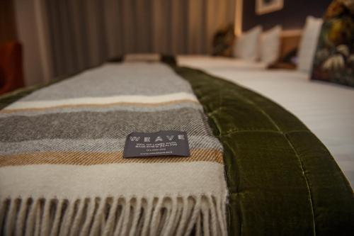 a close up of a bed with a green and white blanket at The Langlands Hotel in Invercargill