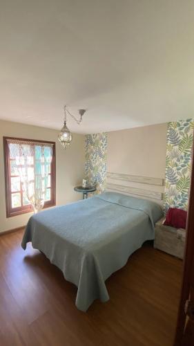 a bedroom with a large bed with a blue blanket at Cabaña Sol y Luna in Villa Serrana