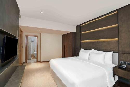 a bedroom with a large white bed and a television at Vasa Hotel Surabaya in Surabaya