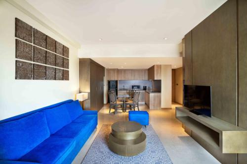 a living room with a blue couch and a kitchen at Vasa Hotel Surabaya in Surabaya
