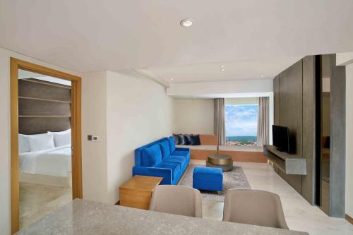 a hotel room with a bed and a blue chair at Vasa Hotel Surabaya in Surabaya