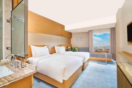 two beds in a hotel room with a view at Vasa Hotel Surabaya in Surabaya
