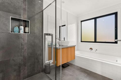 La salle de bains est pourvue d'une baignoire, d'un lavabo et d'une douche. dans l'établissement Castlebay, à Wimbledon Heights
