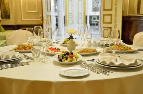 a table with plates of food and wine glasses at Rixos Khadisha Shymkent in Shymkent
