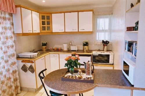 a kitchen with a table with flowers on it at Anchor's Rest Guesthouse and Self Catering in Durban